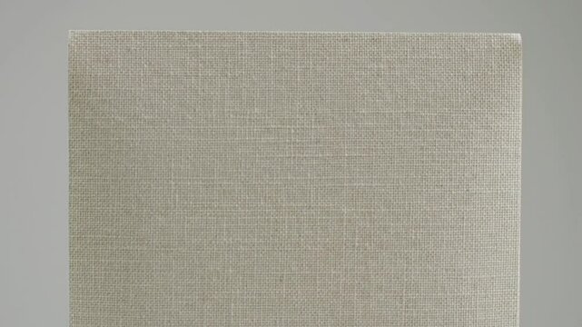 A close up of a cream colored paper standing upright with a slight curve against a grey background