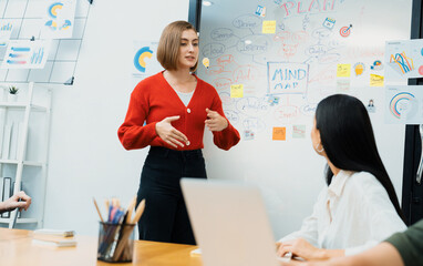 Professional attractive female leader presents creative marketing plan by using brainstorming mind mapping statistic graph and colorful sticky note at modern business meeting room. Immaculate.