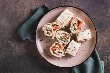Close up of chicken meat, pepper and cucumber in sauce wrapped in tortilla rolls on a plate top view