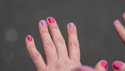 Hands with pink and purple nail polish.