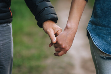 Adult man and woman, elderly people holding hands outdoors.