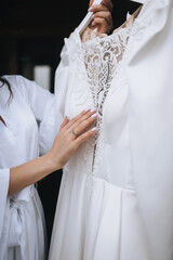 Young bride in lingerie holding white lace dress in hand in the morning. Wedding photography.
