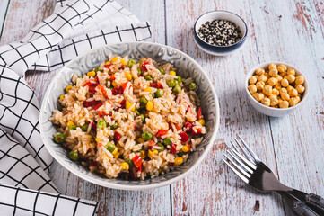 A bowl of cooked rice and vegetables for garnish on the table