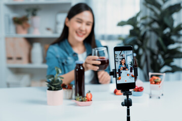 Selective focus smartphone with smiling young beautiful Asian reviewing mixed strawberry and cherry...