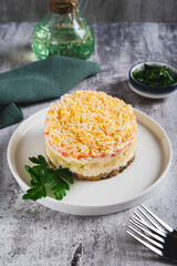 Classic mimosa salad with canned fish and vegetables on a plate on the table vertical view