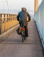 Cyclist in black riding bridge path.