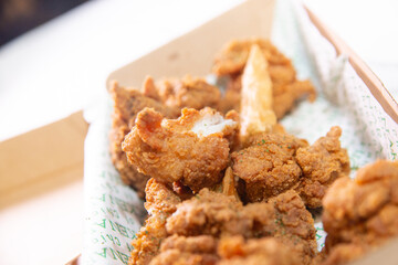 Korean deep dried chicken in paper brown take out box.