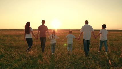 Big active family in summer go on green grass in meadow. Parents children walking in summer nature...