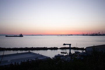 Nave cargo e porto industriale al tramonto sul mare