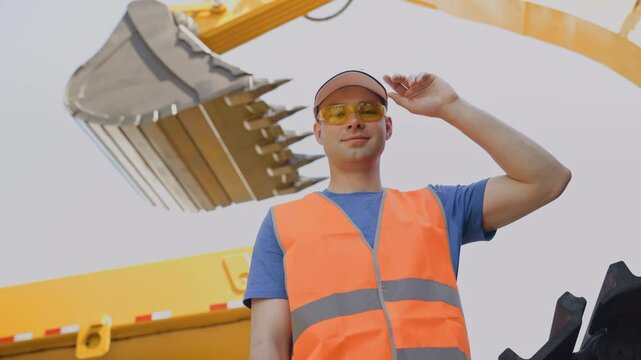 Portrait of industrial worker driver in uniform against background of excavator. People of industry hard work.