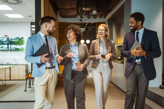 Multicultural colleagues talk and smile while walk through the company