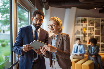 Couple of male and female colleagues use tablet and discuss work
