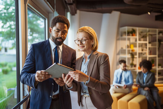 Couple of male and female colleagues use tablet and discuss work