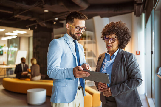 male and female colleagues use tablet together and discuss work - Powered by Adobe