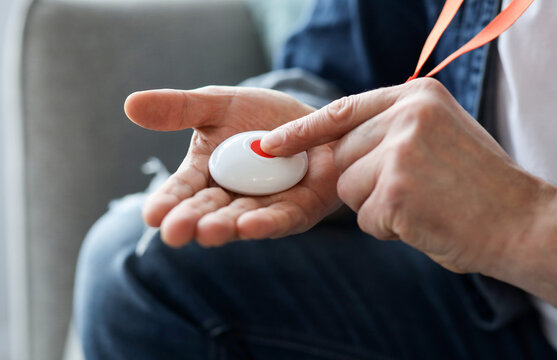 Closeup of man's hand pressing alarm button for emergency on his chest, home interior. Unrecognizable mature man pushing panic button on emergency equipment for elderly people, cropped