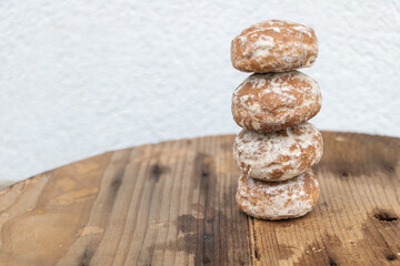 A stack of small, round gingerbread cookies dusted with icing stands on an old wooden table against...