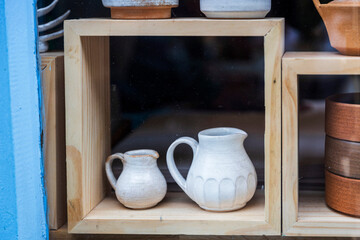 Ceramic jugs are on a wooden shelf.