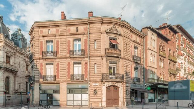 Panorama showing historic brick facades at Rue du Languedoc and Theodore Ozenne intersection timelapse in Toulouse, France. Shops, cafes, road traffic near Carmes metro station in vibrant city center