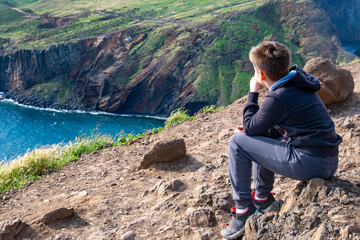 teenager traveler, boy 10-12 years old gazing at ocean from high trail, peaceful mountain coast...