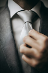 Close-up of a man adjusting his tie in a formal setting