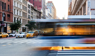 City bus driving through the busy intersection of 5th Avenue and 23rd Street in New York City with motion blur