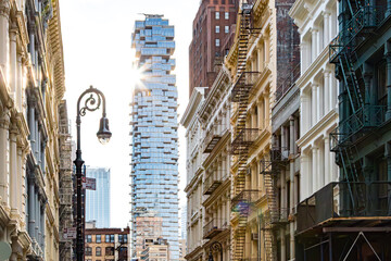 Old historic buildings contrast against a modern glass skyscraper on Greene Street in the SoHo neighborhood of New York City
