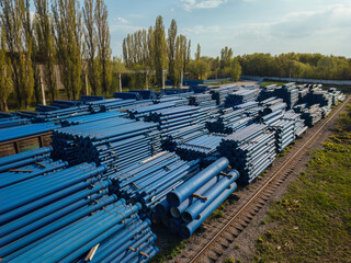 Stack of cast iron pipes in loading area waiting for transportation, drone aerial view
