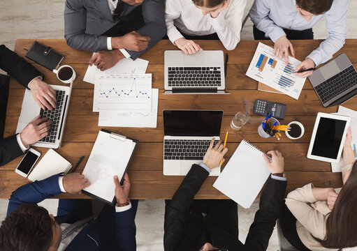 Diverse business team at meeting, discussing marketing strategy and working on gadgets, top view - Powered by Adobe