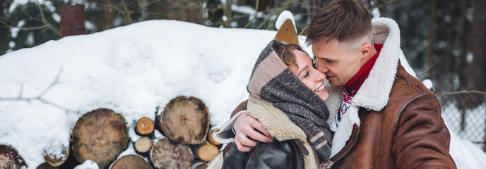 Happy young loving couple celebrating New Year or Christmas outdoors in a countryside holding sparklers, smiling, laughing, embracing, kissing. Togetherness on holiday time, winter leisure activities