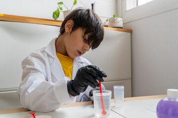 Boy doing science experiment at home with protective gloves