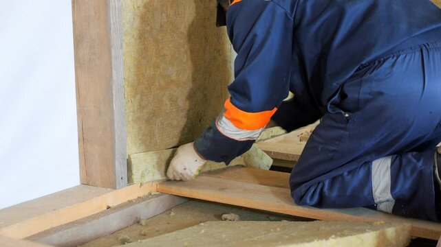 Insulation of a frame house with mineral wool. Cutting, fitting, laying insulation. Construction works.