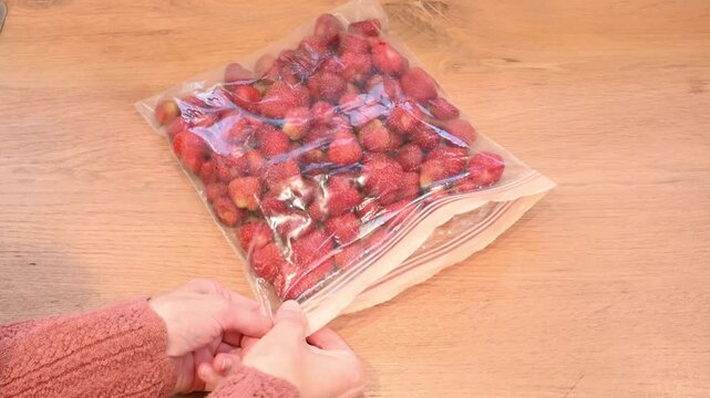 Woman Zipping Freezer Bag of Strawberries on Kitchen Counter - Copy Space