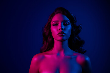 Elegant young woman with neon lighting in blue and pink tones conveying beauty and fashion in a sensual portrayal