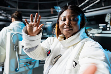 Astronaut wearing spacesuit inside futuristic spacecraft relaying mission data back to Earth....