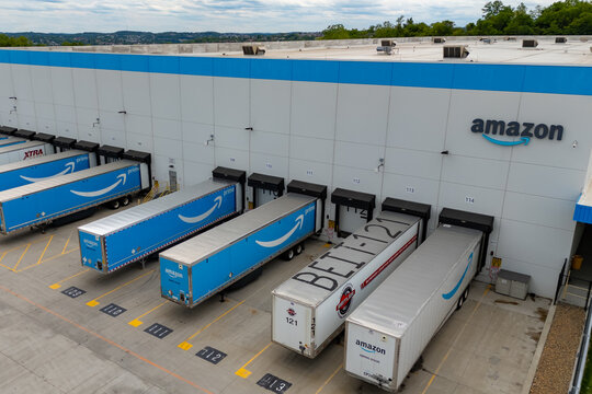 Pittsburgh.Pennsylvania.USA-05.25.2025: Aerial view of an Amazon distribution center with multiple Prime delivery trucks backed into loading docks. The facility is surrounded by a concrete yard and gr