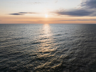 Obraz premium An aerial drone view of the serene Baltic Sea during the summer White Nights, with the low sun reflecting on the calm waves.