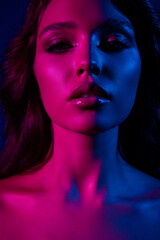 Portrait of a young woman in neon lighting with blue and pink highlights, showcasing beauty, fashion, and elegance