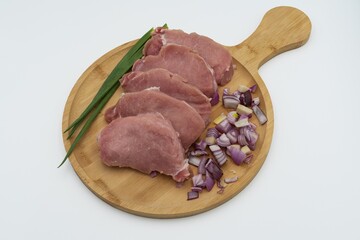 Raw pork steaks with sliced ​​red onion and green onion on wooden board ready to cook