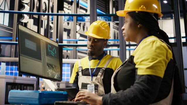 Manager supervising technician in industrial plant using PC software to diagnose malfunctions. Factory team leader working with coworker to coordinate repair tasks on assembly lines, camera A