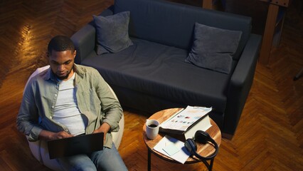 African american casual man solving daily tasks on his laptop at home, doing remote freelance work...