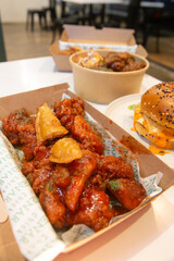 Korean deep dried spicy red chicken sauce in a paper takeaway box.