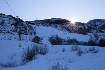 Seggiovia in montagna al tramonto con pista da sci innevata
