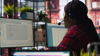 IT support specialist at PC in office helping customers during call, troubleshooting errors. Tech support agent at desk looking at computer monitor, fixing technical issues for clients, camera A
