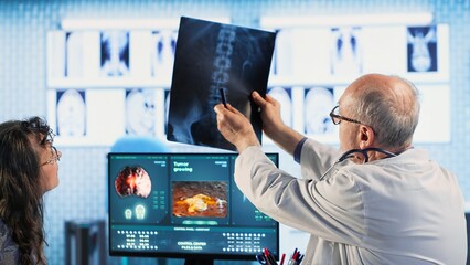 Skilled radiologist uses medical imaging technology to assess cancer risk factors, guiding old female patient through early detection and treatment options. Preventative medicine. Camera B.