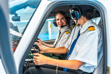 Female pilots operating cockpit controls inside aircraft © unai