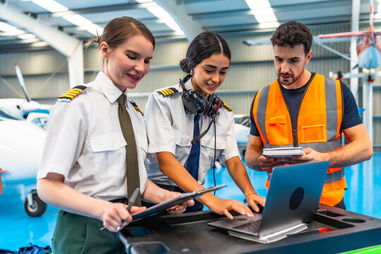 Aircraft maintenance team using laptop for airplane checkup in hangar