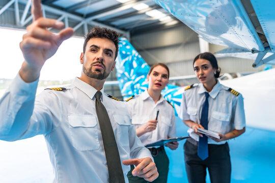 Aircraft maintenance crew inspecting airplane wing in hangar