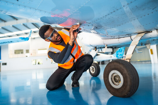 Aircraft maintenance engineer inspecting airplane wing in hangar