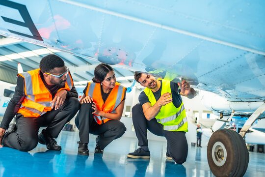 Aircraft maintenance technicians inspecting airplane fuselage in hangar - Powered by Adobe