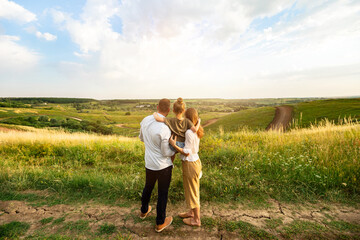 Happy Family Concept. Back view of mother, father and daughter looking and enjoying landscape on...